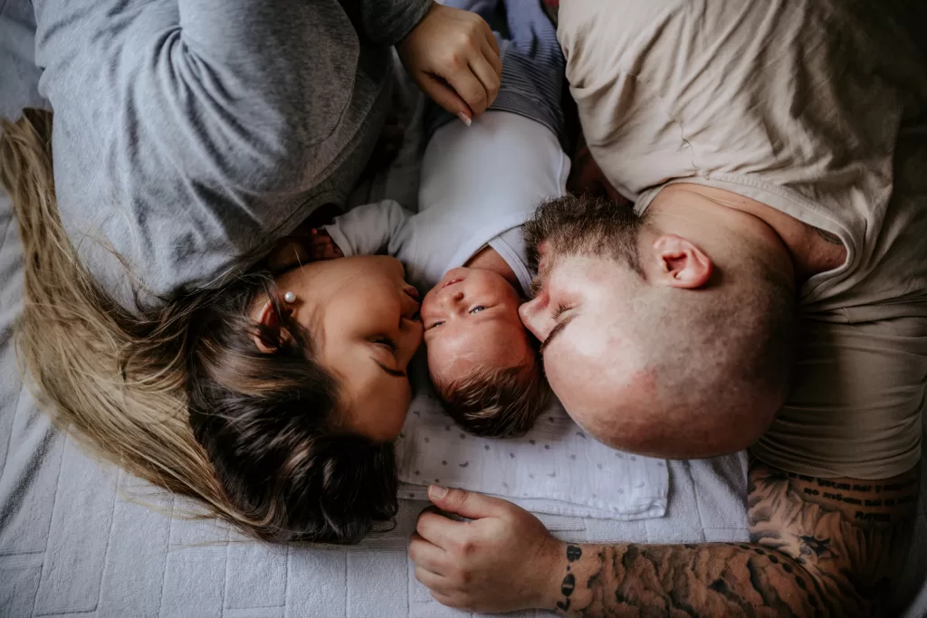 A smiling couple holding their newborn baby, representing successful holistic fertility treatment.