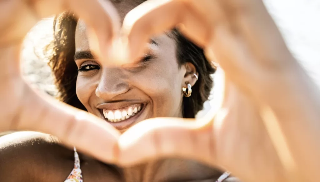 Woman making a heart with her hands around her face, symbolizing menstrual health, women's wellness, and pain relief