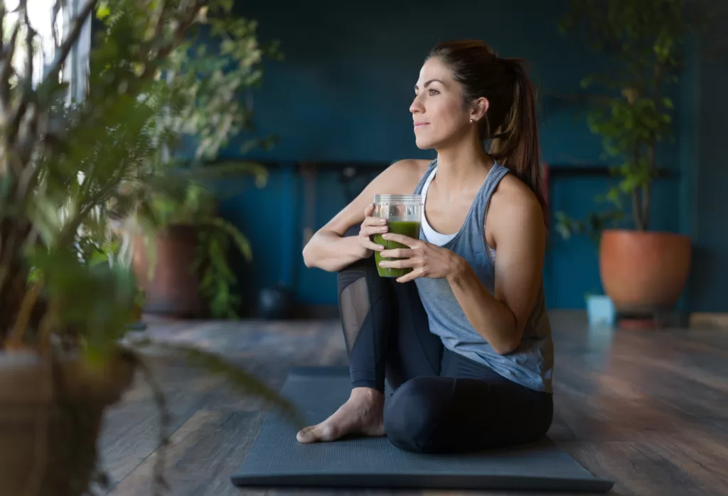 Woman holding a green smoothie, representing stress management and emotional well-being