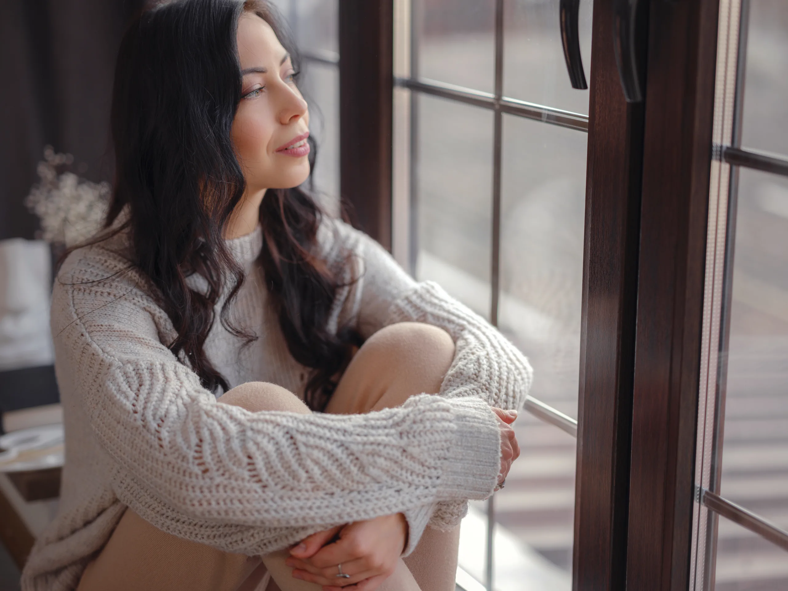 Woman sitting by a window in quiet reflection, representing thoughtful fertility and hormone care in Salt Lake City.